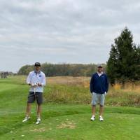 Four alumni standing together on golf course